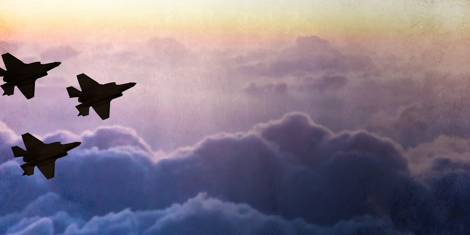 Silhouettes of three F-35 aircraft on sunset sky background