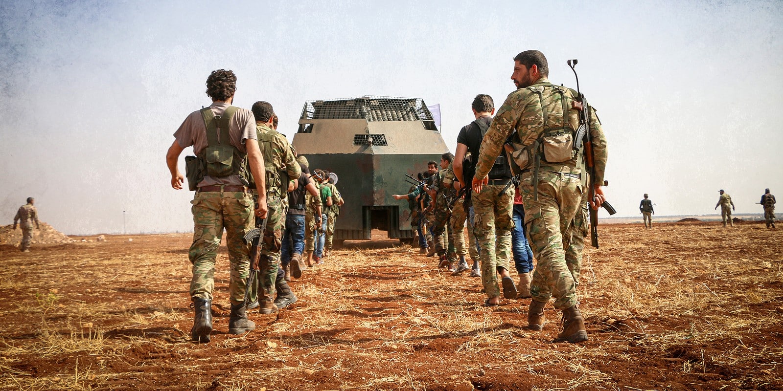 Aleppo, Syria 01 January 2017:\\nA group of fighters walks behind a military mine sweeper.