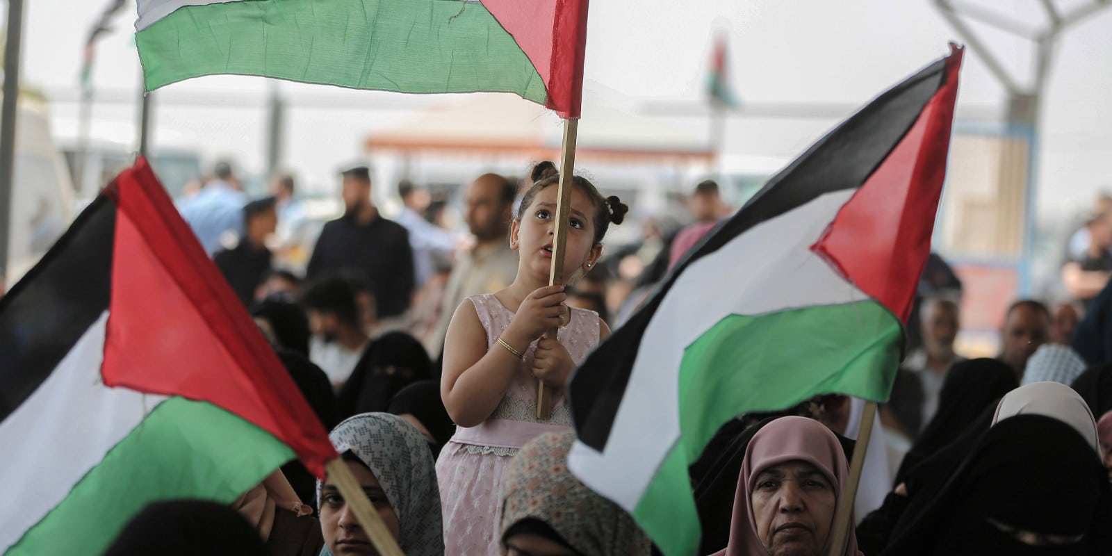 A Palestinian child holds a Palestinian flag